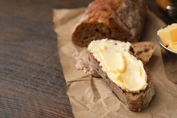 Tasty bread with butter on wooden table, closeup. Space for text