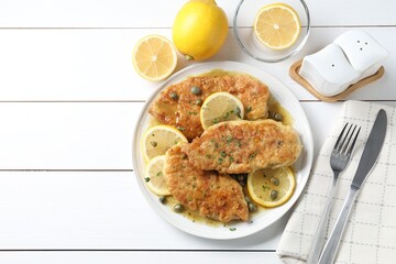 Delicious chicken piccata served on white wooden table, flat lay. Space for text