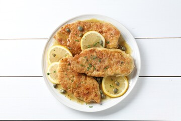 Delicious chicken piccata on white wooden table, top view