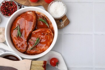 Flat lay composition with raw marinated meat in bowl, spices and basting brush on white tiled...
