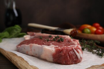 Raw meat and thyme on wooden table, closeup