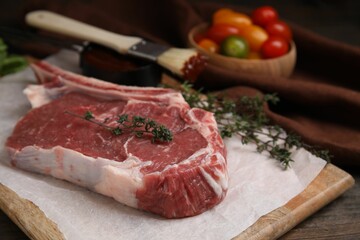 Raw meat and thyme on wooden table, closeup
