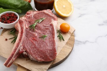 Raw meat, rosemary and products on white marble table, closeup. Space for text