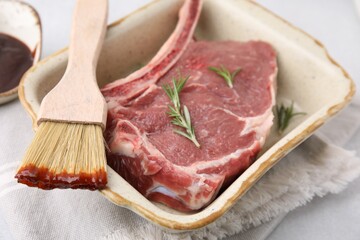 Raw meat, rosemary and brush with marinade on light table, closeup