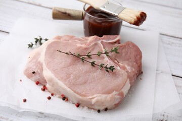 Raw meat, thyme, spices and marinade on white wooden table, closeup