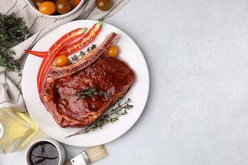 Raw marinated meat with thyme, chili pepper and basting brush on light table, flat lay. Space for...