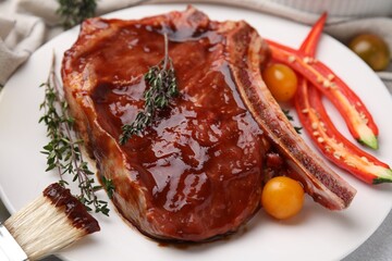 Raw marinated meat with thyme, chili pepper and basting brush on light table, closeup