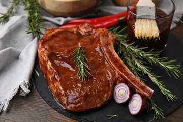 Tasty marinated meat, rosemary and onion on wooden table, closeup
