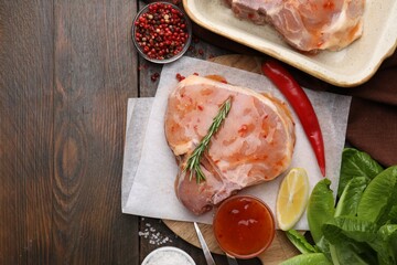 Flat lay composition with raw marinated meat, lemon, rosemary and spices on wooden table. Space for...