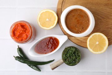 Different marinades and products on white tiled table, flat lay