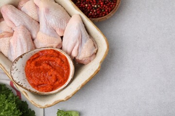 Flat lay composition with marinade, raw chicken and other products on light textured table. Space for text