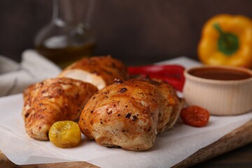 Baked chicken fillets and marinade on wooden table, closeup