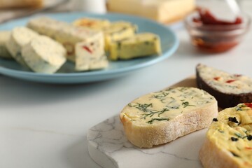 Different types of tasty butter and bread on white table, closeup