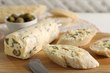 Tasty butter with olives, green onion and bread on wooden board, closeup