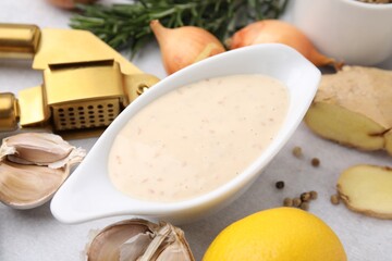 Fresh marinade, garlic press and different ingredients on light grey table, closeup