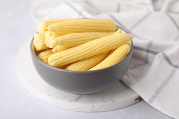 Tasty fresh yellow baby corns in bowl on white table