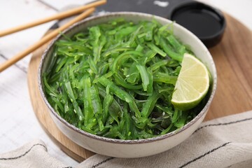 Tasty seaweed salad in bowl served on wooden table, closeup