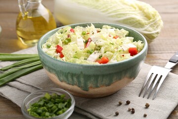 Tasty salad with Chinese cabbage in bowl, peppercorns and green onion on wooden table, closeup