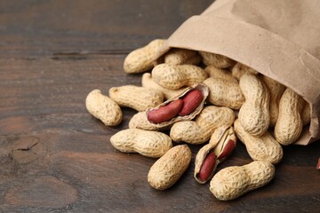 Paper bag with fresh peanuts on wooden table, closeup. Space for text