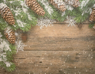 Christmas composition. Frame made of pine branches, fir cones and snowflakes on rustic vintage wooden background