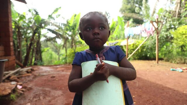 A young girl is holding a piece of paper and a pencil, she is ready for her first day of school