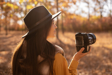 beautiful woman photographer taking photos in autumn forest using SLR camera - obrazy, fototapety, plakaty