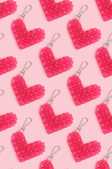 Repetitive pattern made from beaded heart keychains on a pink background. Creative layout.