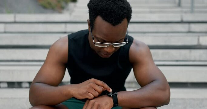 Black man, smart watch and stairs with fitness, exercise and training with break and checking time. Steps, African person and athlete with goals, progress and tracker with hobby and app with workout