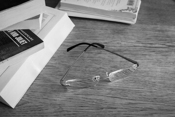 Classic glasses and pile of books on the table, monochrome. Literature concept. Eyeglasses next to...
