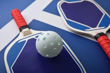 Tuinposter Detail of blue and red pickleball paddles on playing court © Davizro Photography