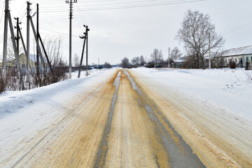 Rural winter road sprinkled with sand against ice