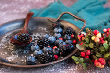 Blackberries and blueberries on a metal platter. Summer harvest of cranberries