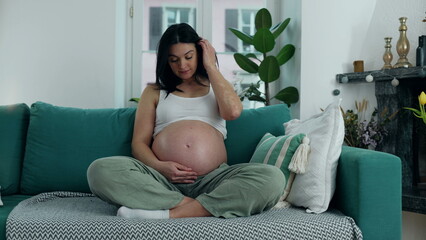 Joyful Expectation - Cheerful Pregnant Woman Relaxing on Sofa, Beaming with Happiness in the Late Stage of Her Third Trimester at Home