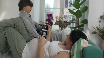 Mother and Son Sharing Happy Tender Moment, Looking at Baby Brother's Ultrasound While Resting on...
