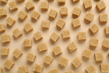 Brown sugar cubes on beige background, top view