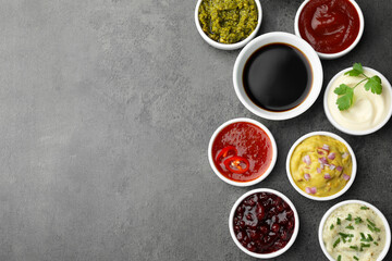 Different tasty sauces in bowls on grey table, flat lay. Space for text