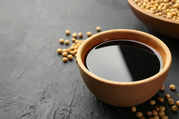 Fototapeten Tasty soy sauce in bowl and soybeans on black table, closeup. Space for text © New Africa