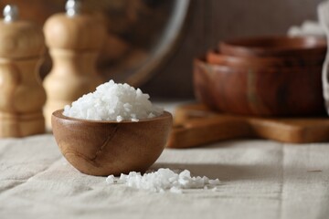 Fototapeta na wymiar Organic salt in wooden bowl on table, closeup. Space for text