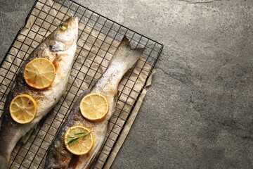 Baked fish with lemon on grey textured table, top view. Space for text