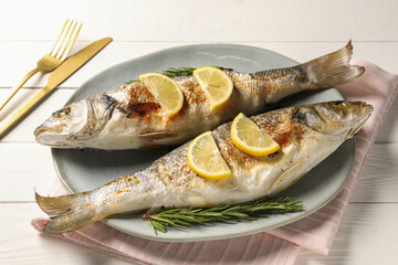 Delicious baked fish served on white wooden table