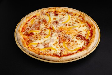 Top view of a pizza with ham, bell peppers, and melted cheese on a black background