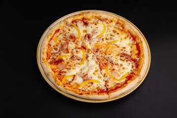 Top view of a delicious pizza with ham and bell peppers isolated on a black background