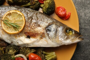 Delicious baked fish and vegetables on grey background, top view