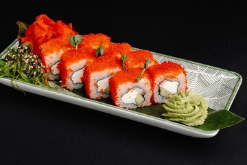 Sushi Roll with Caviar, Cream Cheese, Cucumber, and Wasabi on White Plate on Black Background