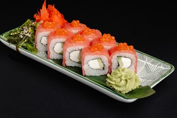 Sushi roll with red caviar, cream cheese, and avocado on a white plate