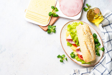 Ciabatta sandwich with lettuce, cheese, tomatoes and ham. Flat lay on white table. - 783196552