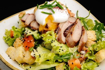 Grilled chicken breast with fresh salad on a white plate and black background