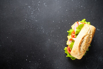 Ciabatta sandwich with lettuce, cheese, tomatoes and ham on black background. Flat lay with copy space. - 783197519