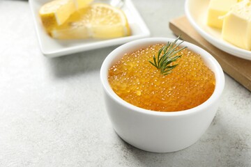 Fresh pike caviar and dill in bowl on light grey table, closeup
