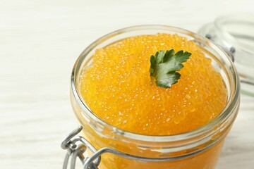 Fresh pike caviar and parsley in glass jar on table, closeup